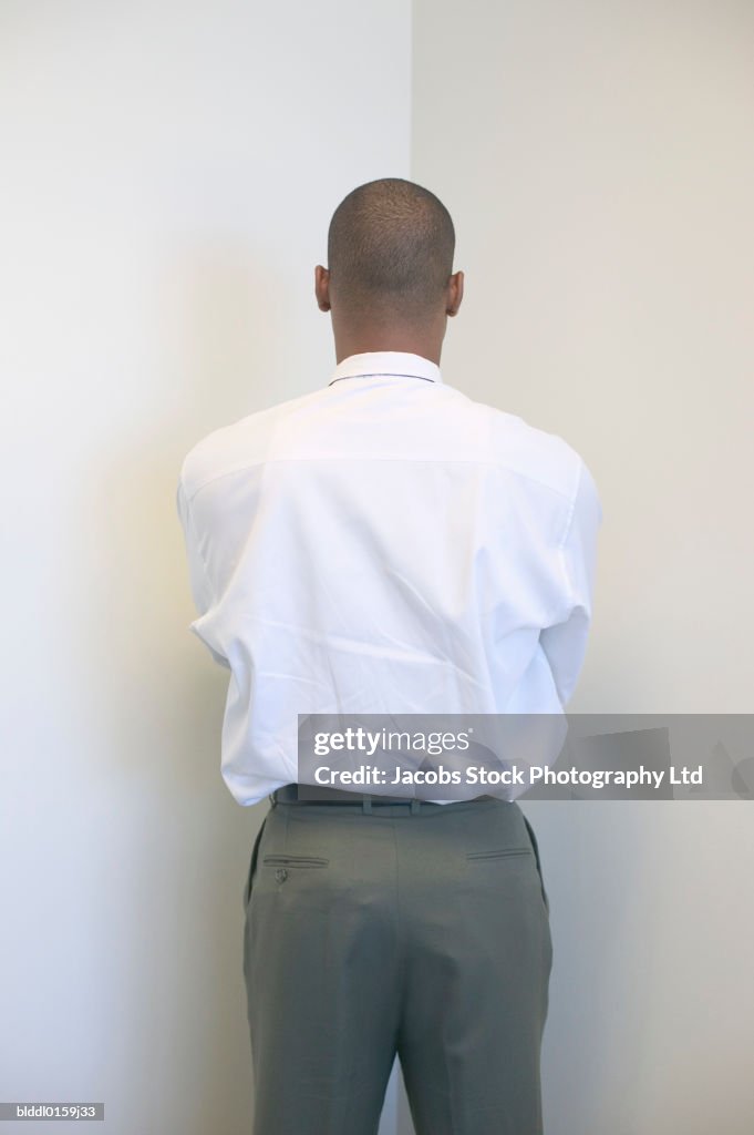 Rear view of a businessman standing facing the wall