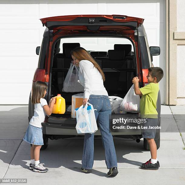 rear view of a mother with her son and daughter unloading shopping bags from a car - girls with short skirts photos et images de collection