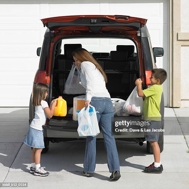 rear view of a mother with her son and daughter unloading shopping bags from a car - unloading 個照片及圖片檔