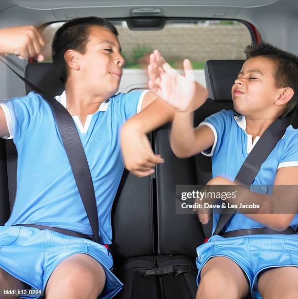 two boys sitting in the back seat of a car and playing - punching stock pictures, royalty-free photos & images