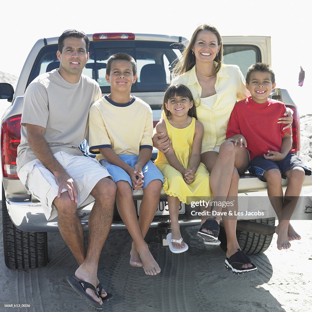 Portrait of a family sitting at the back of a pick-up truck