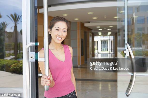 portrait of a businesswoman standing at the entrance door of an office - open collar stockfoto's en -beelden