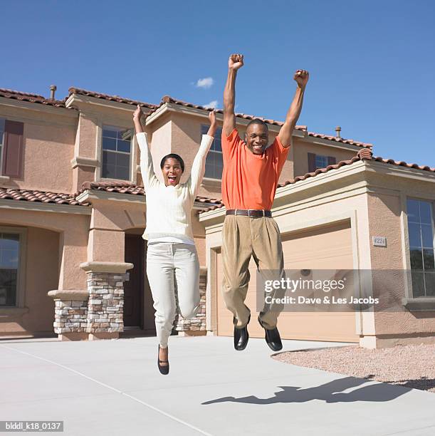 portrait of a mid adult couple jumping - mann freudensprung sonne vorderansicht leger stock-fotos und bilder