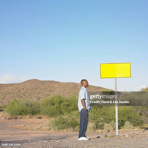 side profile of a mid adult man standing beside a sign board - dave and les jacobs stock-fotos und bilder