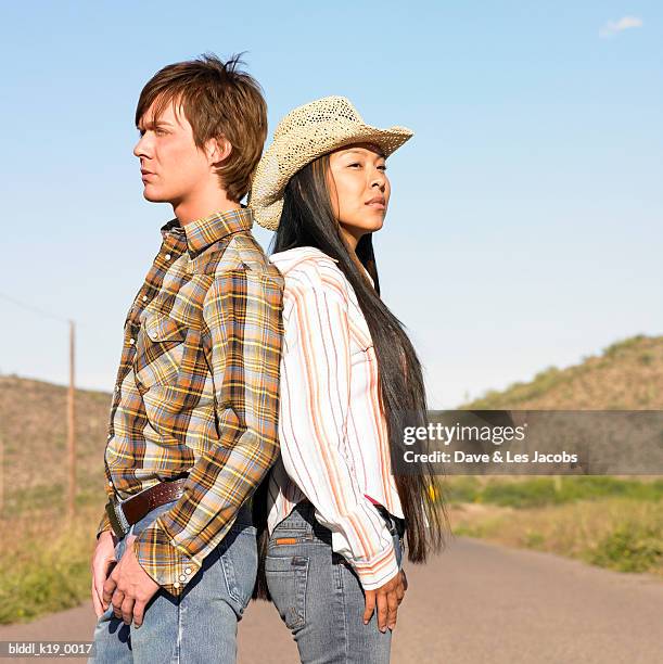 side profile of a young couple standing back to back on the road - dave and les jacobs stock-fotos und bilder