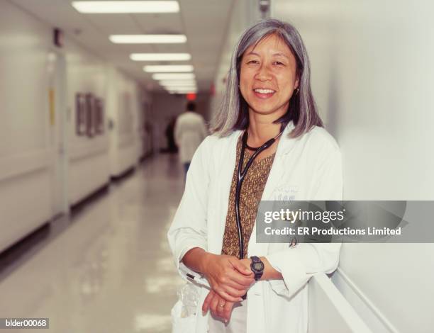 portrait of a female doctor standing in a hospital corridor - er stock-fotos und bilder