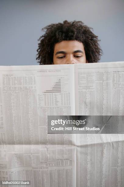 young man reading a newspaper - junger mann liest zeitung stock-fotos und bilder
