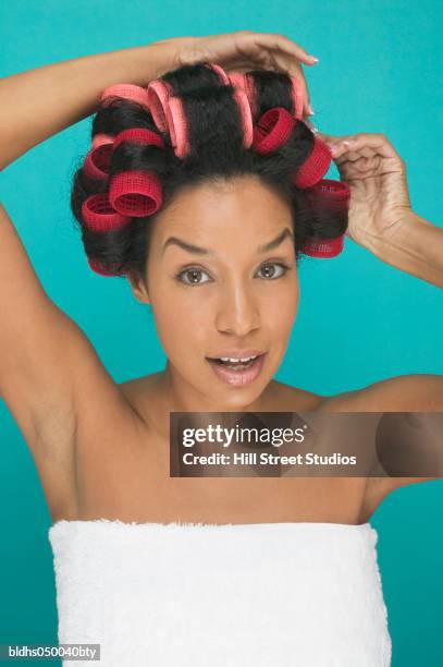 portrait of a young woman fixing curlers in her hair - hair curlers stockfoto's en -beelden