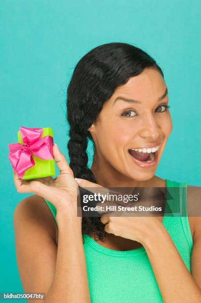 portrait of a young woman pointing to a gift - ribbon in mouth stock pictures, royalty-free photos & images