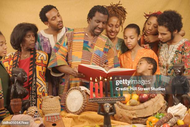 family lighting candles celebrating kwanzaa - kwanzaa celebration stock pictures, royalty-free photos & images