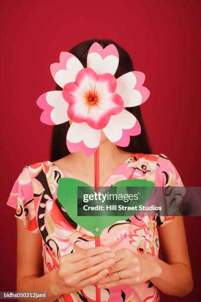 young woman holding an artificial flower - hill street studios stock-fotos und bilder