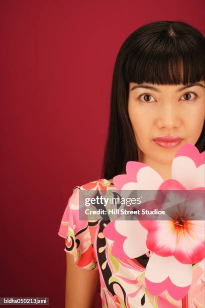 portrait of a young woman holding an artificial flower - hill street studios stock-fotos und bilder