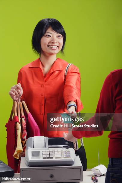 young woman holding a credit card at a checkout counter - hill street studios stock-fotos und bilder