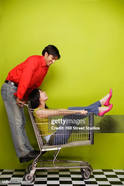 side profile of a young man pushing a young woman in a trolley - hill street studios stock-fotos und bilder