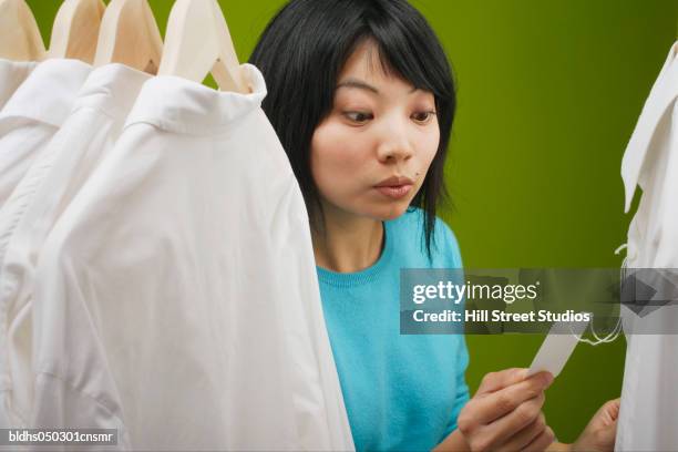 young woman looking at a price tag - tag ストックフォトと画像