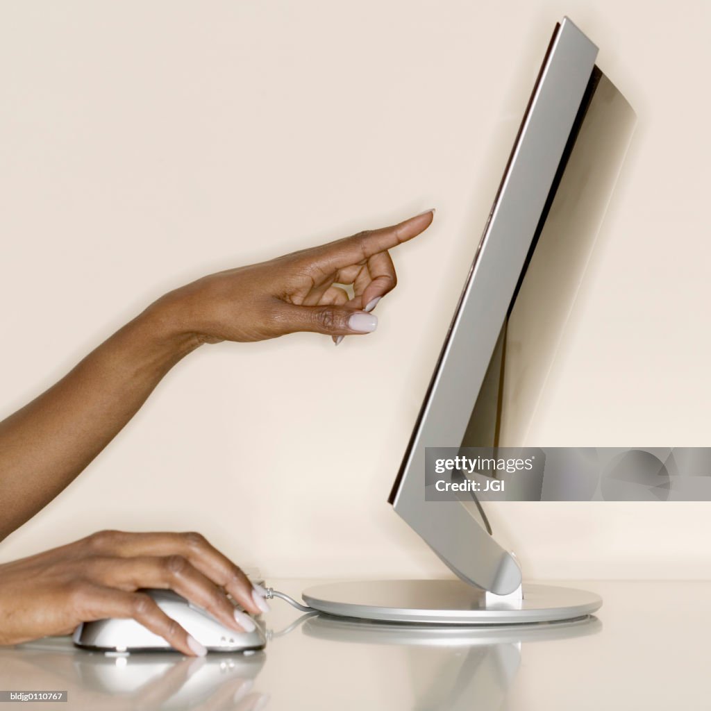 Woman's hands using a computer mouse and pointing at a screen