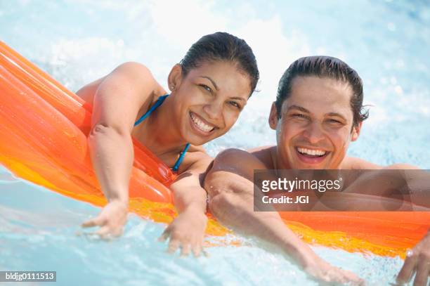 young couple resting on an air mattress in a swimming pool - air date stockfoto's en -beelden