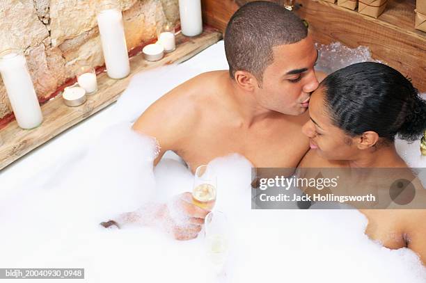 young man kissing young woman in a bathtub - couple and kiss and bathroom stock-fotos und bilder