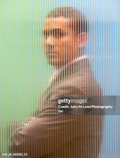 side profile of a businessman standing behind the glass with his arms crossed - frosted glass ストックフォトと画像