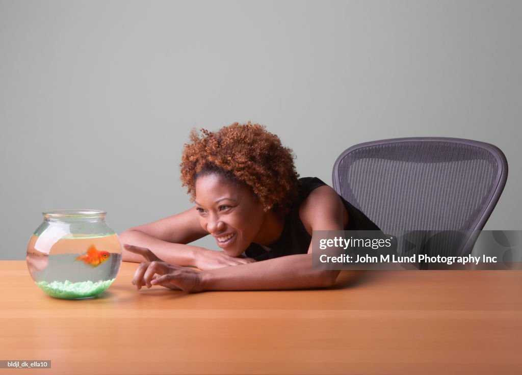 Mid adult woman looking at a fishbowl smiling