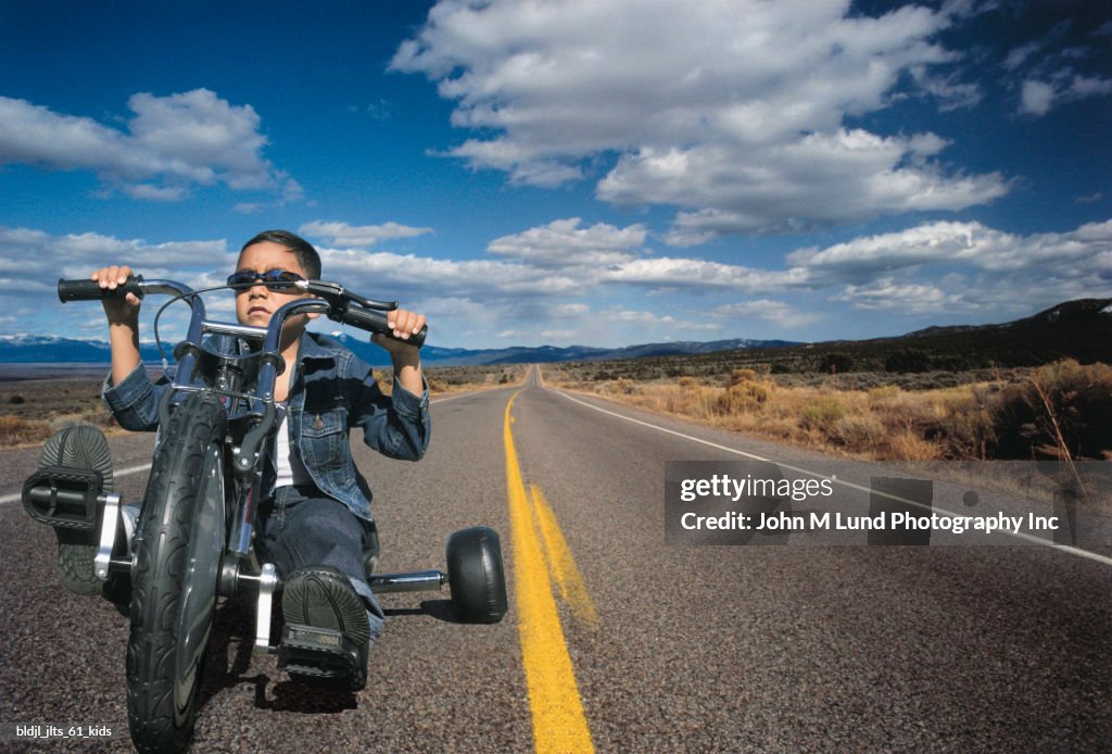 Portrait of a young boy riding a toy motorcycle on a highway