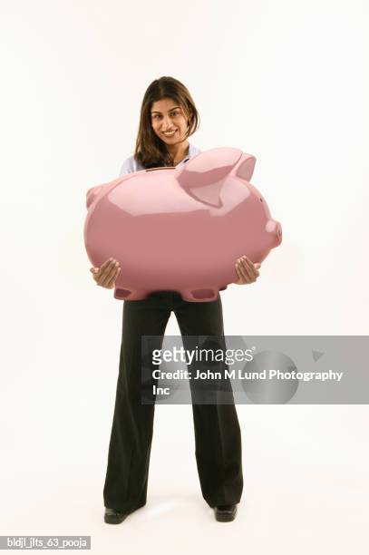 portrait of a young woman holding a large piggybank - john lund ストックフォトと�画像