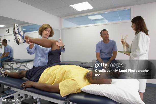 physical therapists treating a patient - john lund stock-fotos und bilder