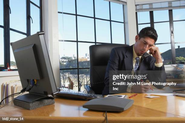 businessman sitting in his office writing on a notepad - john lund ストックフォトと画像