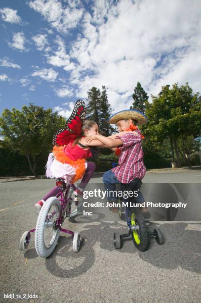 rear view of a young boy and girl sitting on bicycles and fighting - john lund ストックフォトと画像