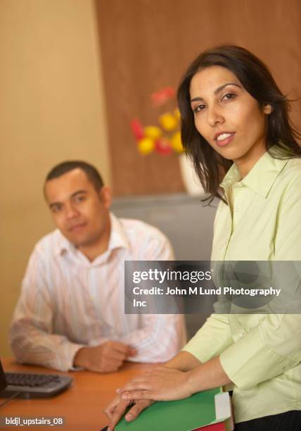 portrait of a businesswoman and a businessman sitting in an office - john lund stock-fotos und bilder