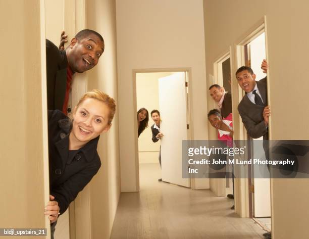 group of business executives peeking out from the doors - john lund stock-fotos und bilder