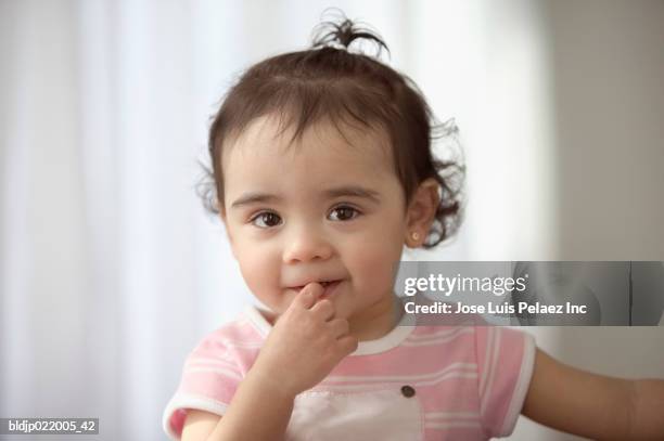 baby girl with her finger in her mouth - 指をくわえる ストックフォトと画像
