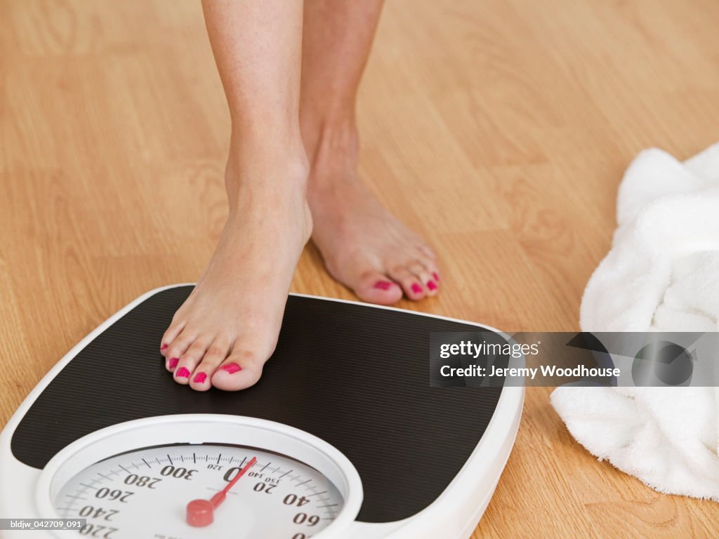 Young woman stepping on a weighing scale