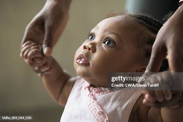 person teaching a baby girl how to walk - african american baby girls stock-fotos und bilder