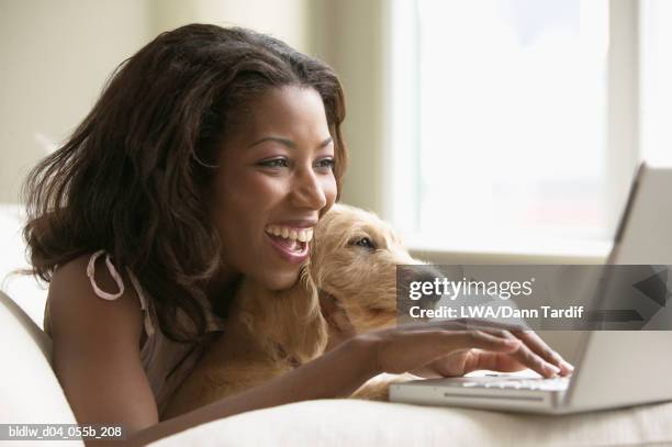 woman working on a laptop with her pet - lwa dann tardif stockfoto's en -beelden