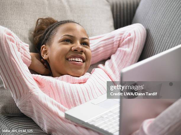 high angle view of a teenage girl lying on a couch with her hands behind her head - lying on back girl on the sofa stock pictures, royalty-free photos & images