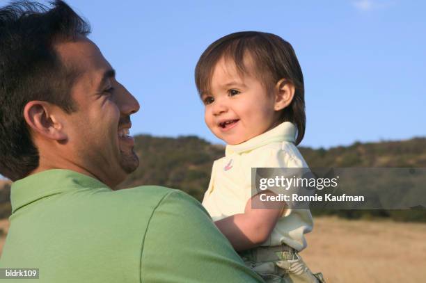 mid adult man holding a baby boy - ronnie kaufman stockfoto's en -beelden