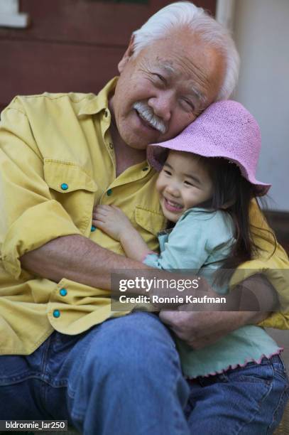 portrait of a senior man embracing his granddaughter - ronnie kaufman stockfoto's en -beelden