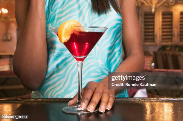 mid section view of a young woman standing at a bar counter with a martini glass - tangerine martini stock pictures, royalty-free photos & images