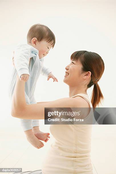 mother lifting up her son - forza fotografías e imágenes de stock