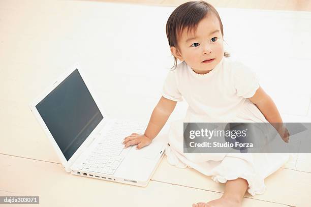 a baby girl playing with a computer - forza fotografías e imágenes de stock