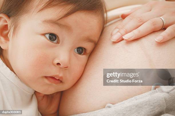 a baby girl put her cheeks on to mothers pregnant stomach - forza fotografías e imágenes de stock