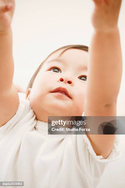 a baby girl stretching her arms - forza fotografías e imágenes de stock