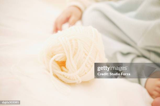 a baby girl's hand and a bowl of yarn - forza fotografías e imágenes de stock