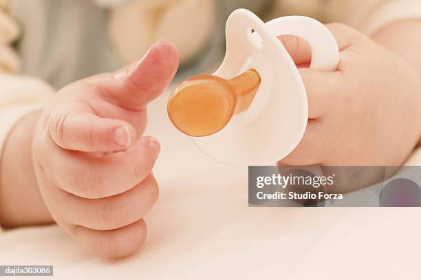 a baby girl's hand and a teething ring - forza fotografías e imágenes de stock