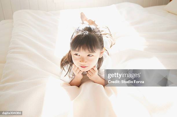 a young girl lying down on the bed - forza fotografías e imágenes de stock