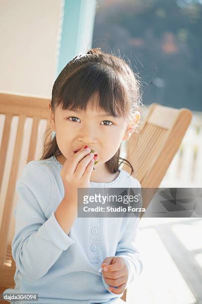 a young girl eating a strawberry - forza fotografías e imágenes de stock