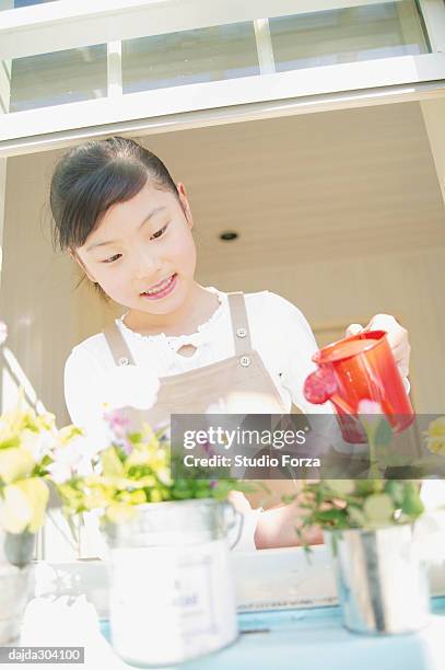 a young girl watering a flower - forza fotografías e imágenes de stock