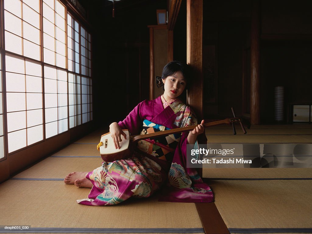 A young woman wearing kimono plays 'samisen'