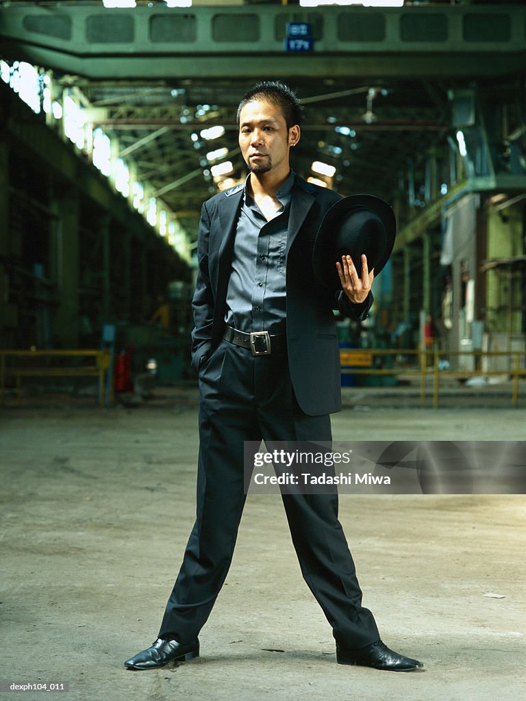 Man with hat and suit, standing in a old warehouse